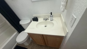 A bathroom with a white sink, a toilet, and wooden cabinets. - Cozy Viva Sanriveria Rental 3Bed2.5 Bath hosts 8 people- near Seaworld,1604 W Lp (San Antonio)