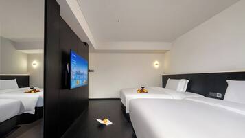 Een hotelkamer met twee bedden, een flatscreen televisie aan de muur en een kleine tafel met fruit en een glas wijn.