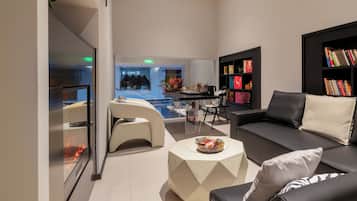 A modern lounge area with a sofa, armchairs, a coffee table, and a bookshelf.