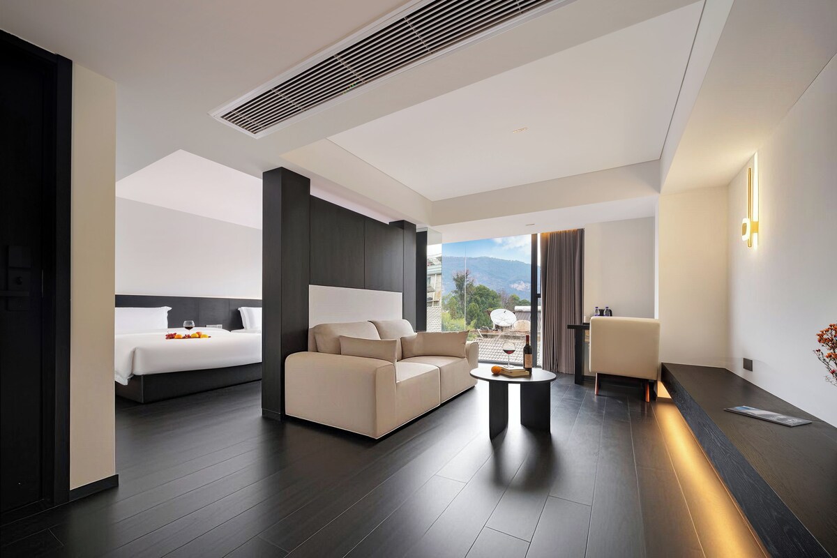 Ein modernes Hotelzimmer mit Bett, Sofa und einem Essbereich mit Tisch.