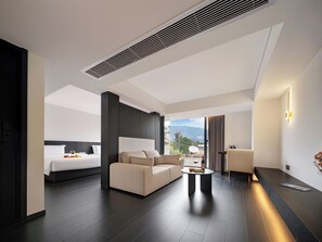 Ein modernes Hotelzimmer mit Bett, Sofa und einem Essbereich mit Tisch.