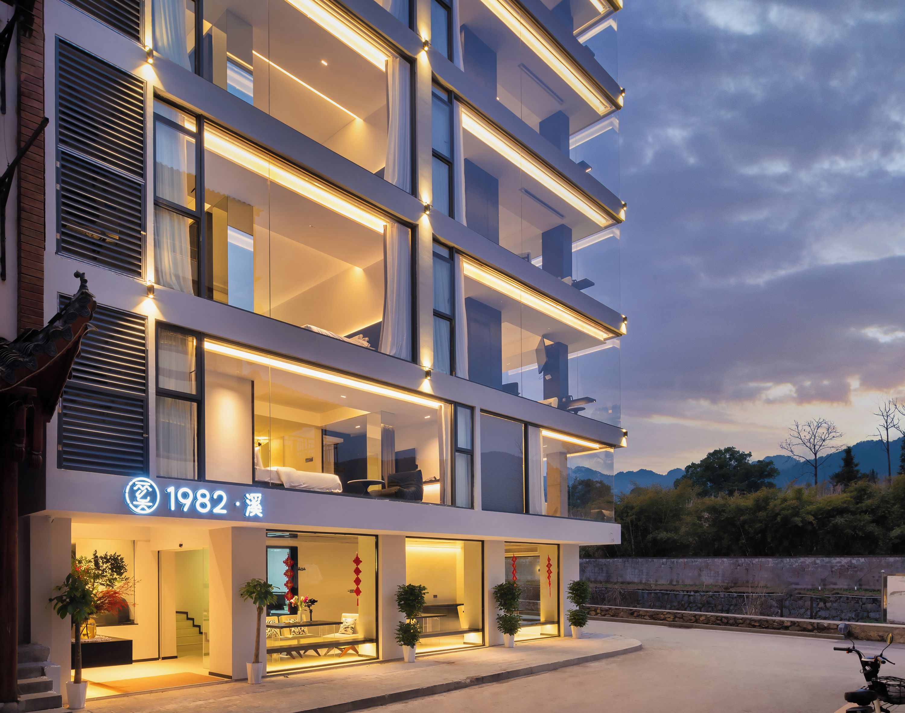 Een modern meerlaags hotel met een zichtbare ingang, een buiten zitgedeelte en een balkon met zitplaatsen.