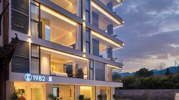 Een modern meerlaags hotel met een zichtbare ingang, een buiten zitgedeelte en een balkon met zitplaatsen.