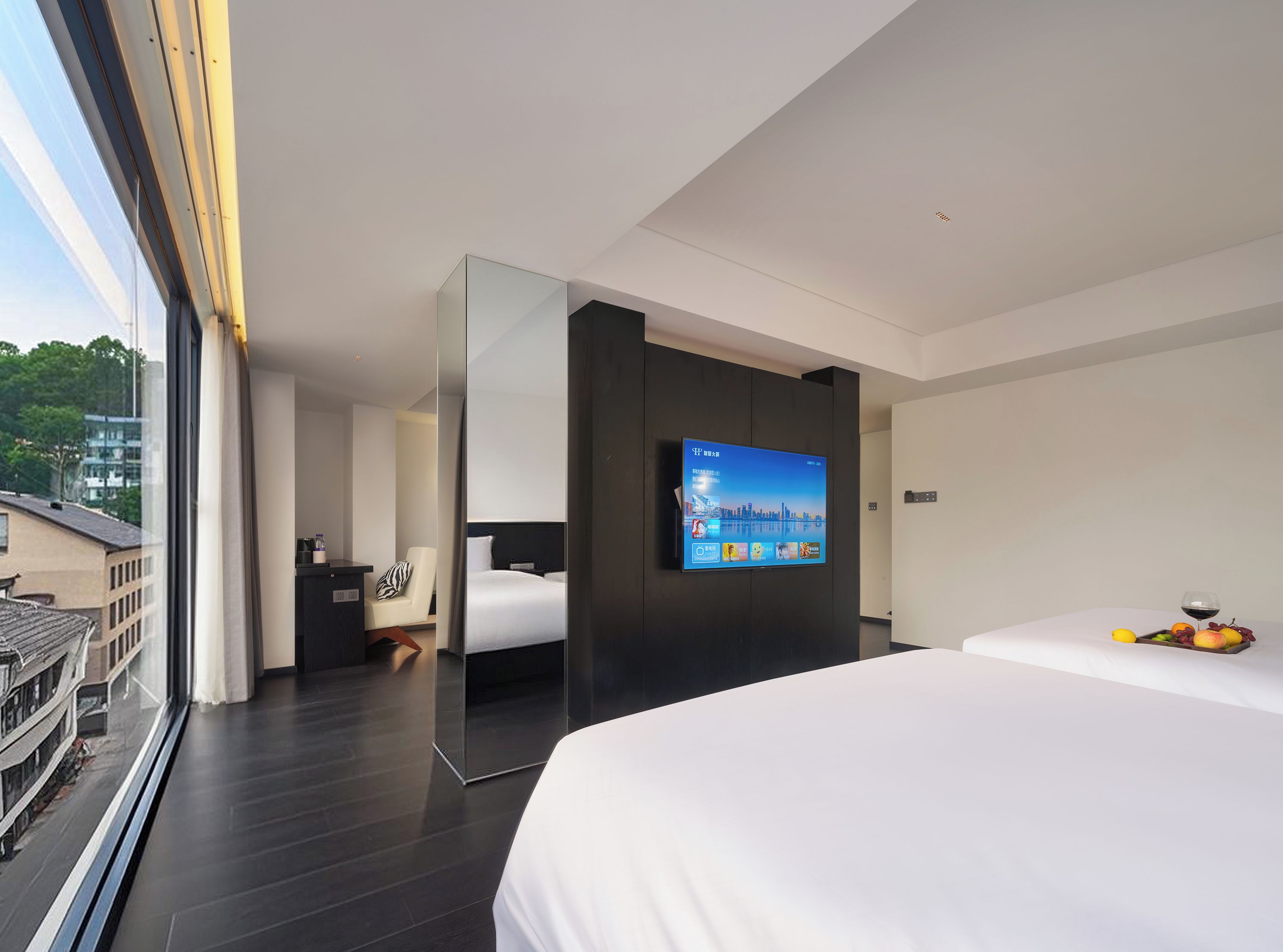 Een moderne hotelkamer met een groot bed, een aan de muur bevestigde televisie en uitzicht op de stad.