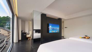Een moderne hotelkamer met een groot bed, een aan de muur bevestigde televisie en uitzicht op de stad.