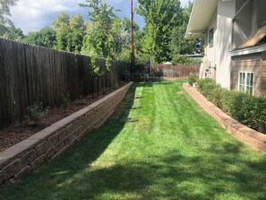 Ein gepflegter Garten mit Holzfence, einer Steinmauer und einem Rasen.
