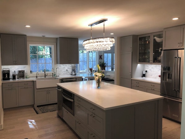 A modern kitchen with a large island, stainless steel appliances, and a chandelier. - Spacious 4-bedroom house on a quiet wooded cul de sac (Boulder)