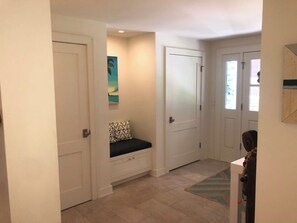 A hallway with white doors, a bench with patterned cushions, and a rug with geometric design. - Spacious 4-bedroom house on a quiet wooded cul de sac (Boulder)