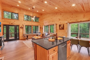 A spacious wooden cabin with a large kitchen, dining area, and a cozy seating space. - Modern Rustic Cabin - Hot tub, Shuffleboard, Pool Table Nestled in Trees (Logan)