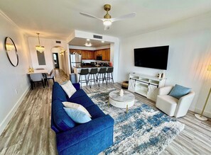 A modern living room with a blue sofa, a coffee table, and a TV. - Balcony Lake Views | Pool, Gym, WiFi & Parking (Orlando)