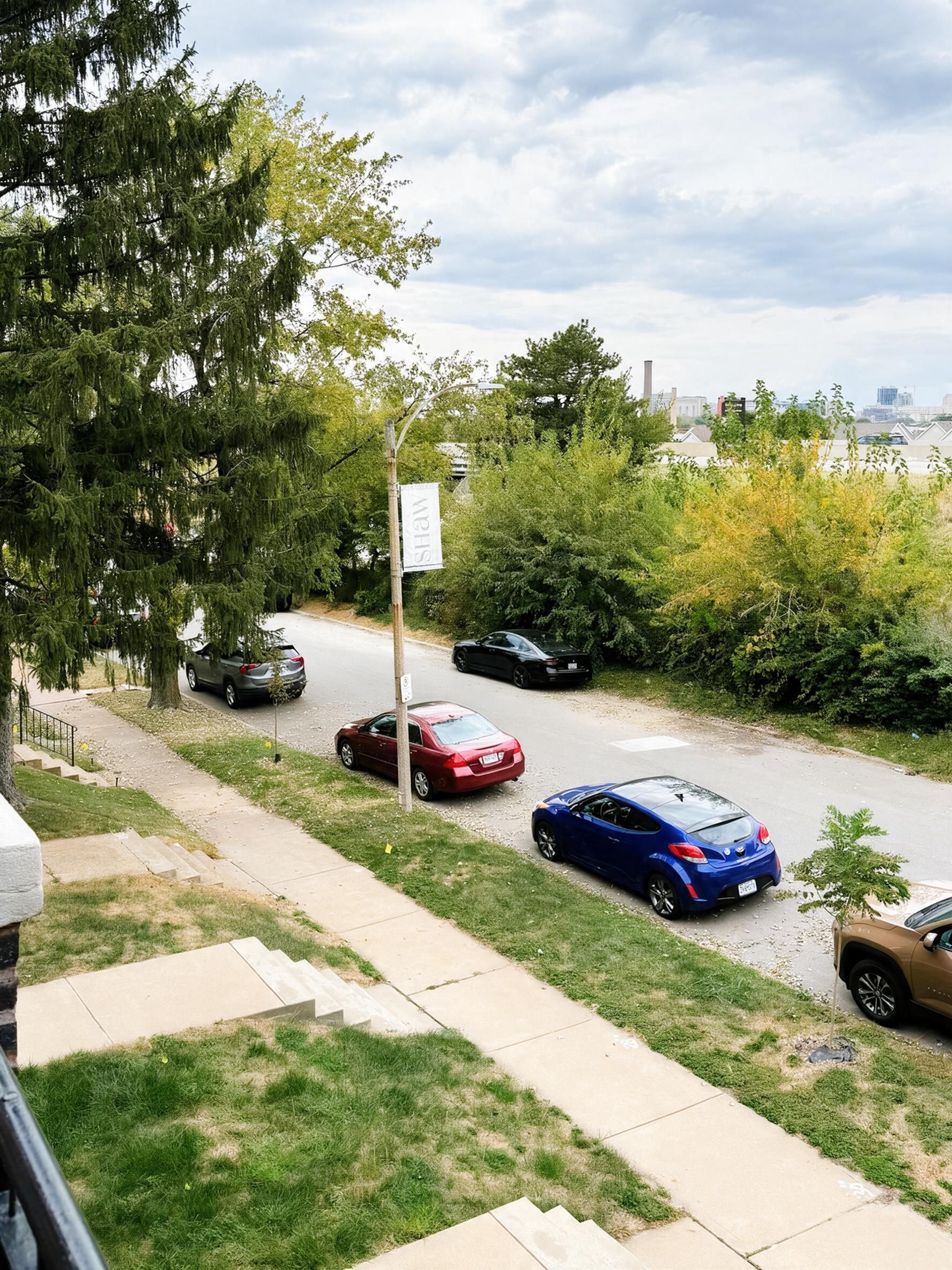 Una calle residencial con coches aparcados y una acera.