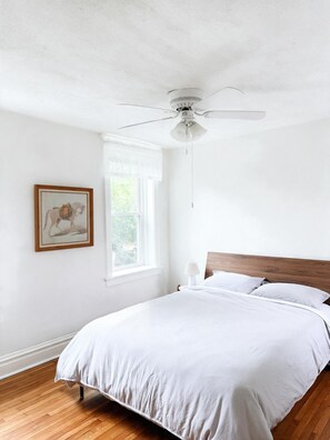 A bedroom with a single bed, a ceiling fan, a window with curtains, and a framed picture on the wall. - Retro 3BR in Historic Shaw · Near Tower Grove Park (St. Louis)