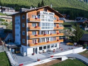 A multi-story hotel with balconies, a covered entrance, and a view of the surrounding area. - Eden 4 OG Brunegghorn, (Grächen), by Interhome (Grächen)
