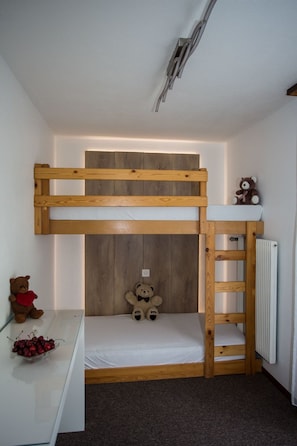 A bunk bed with a wooden frame, a white mattress, and a teddy bear on the top bunk. - Eden 4 OG Brunegghorn, (Grächen), by Interhome (Grächen)