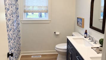 A bathroom with a toilet, sink, mirror, and shower curtain.