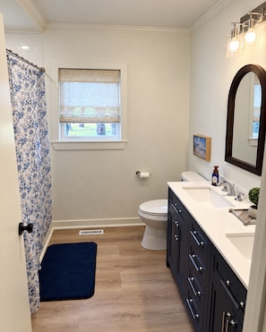 Une salle de bain équipée de toilettes, d’un lavabo, d’un miroir et d’un rideau de douche.