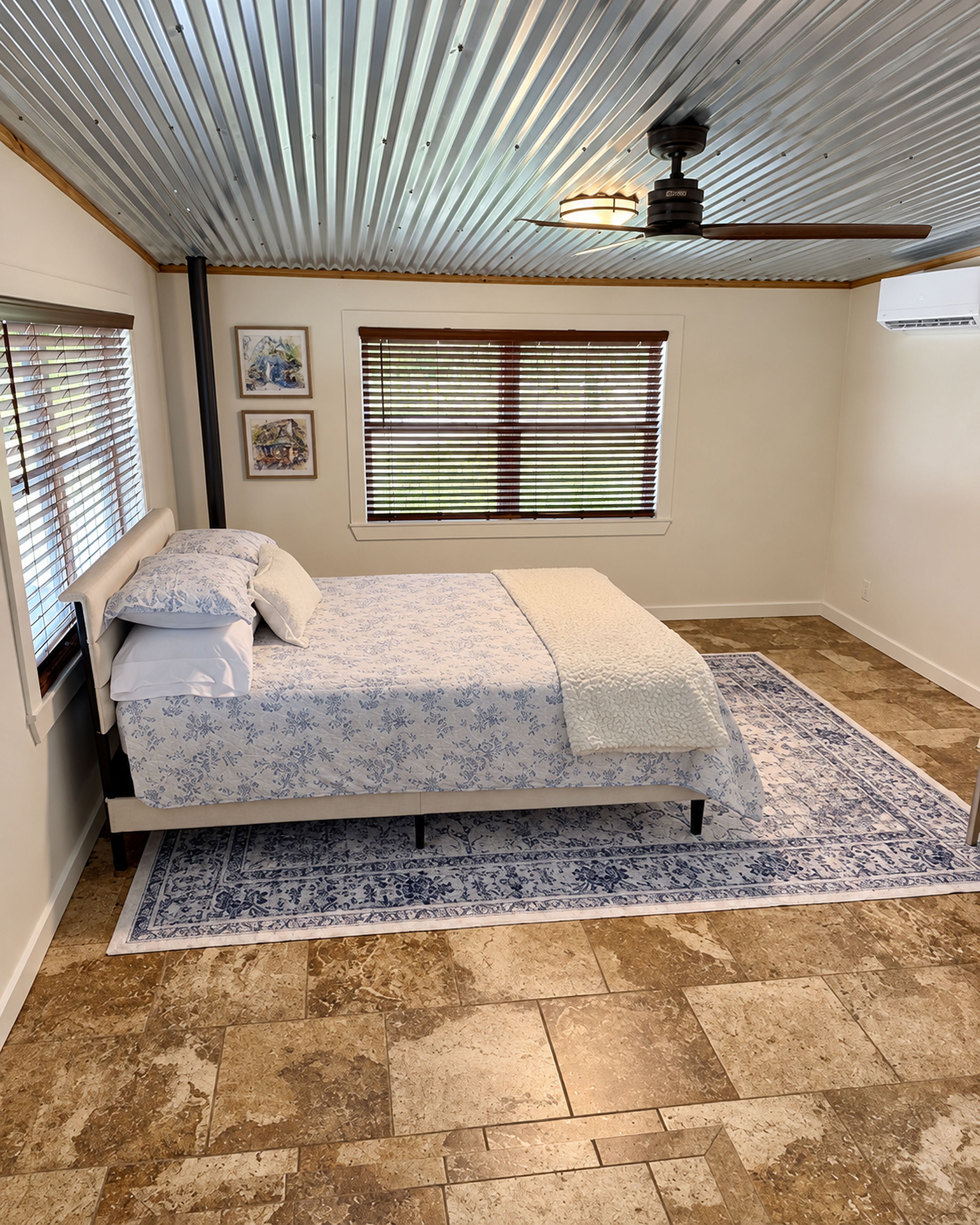 A bedroom with a bed, a window with blinds, a ceiling fan, and a rug.