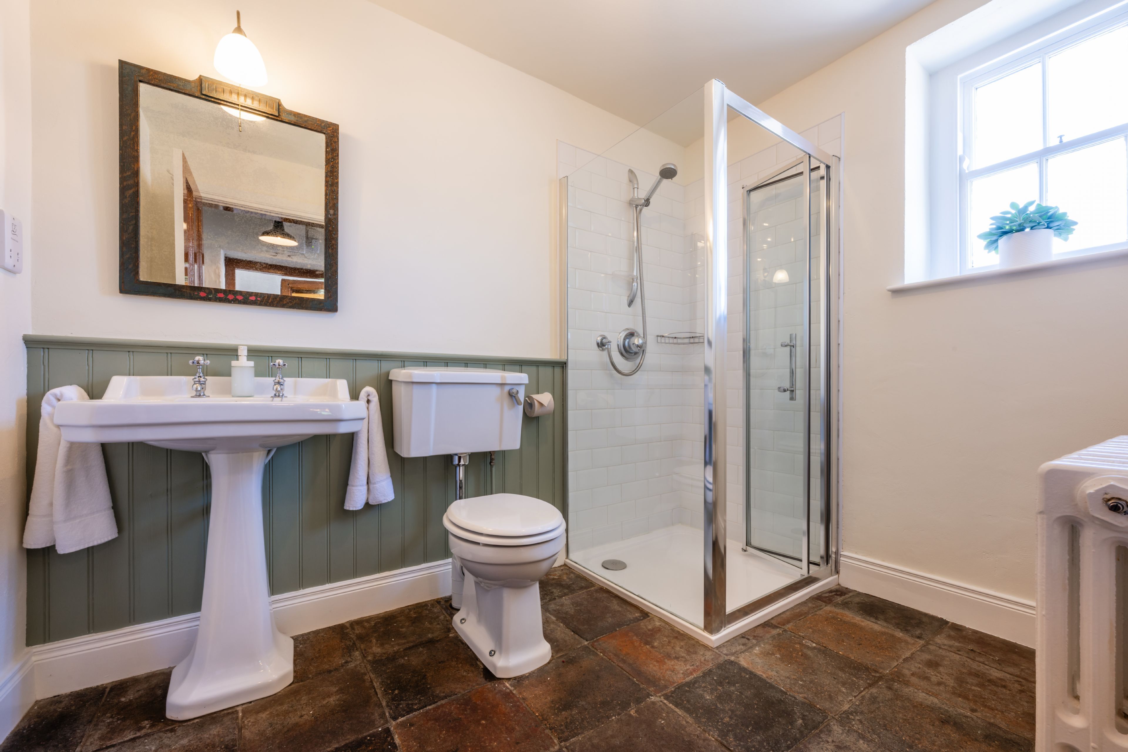 A bathroom with a pedestal sink, toilet, and a glass-enclosed shower.