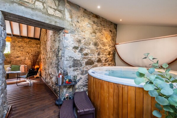 A stone-walled room with a wooden floor, a hot tub, and a seating area with a table and chairs. - Tullymurry House - Fabulous 5-bedroom Country House and Spa - 4 Star (Newry)