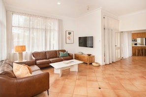 Ein Wohnzimmer mit einem braunen Ledersofa, einem weißen Couchtisch und einem Fernseher an der Wand.