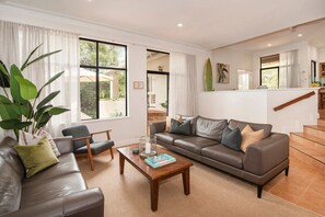Ein modernes Wohnzimmer mit Ledersofa, Couchtisch aus Holz und einer großen Pflanze.