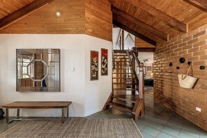 Een rustiek interieur met een houten trap, een bankje en een mand aan de muur.