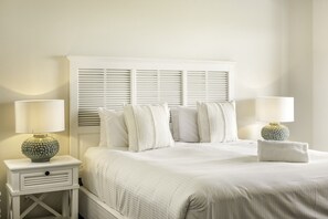 A neatly made bed with white linens and pillows, flanked by two bedside tables with lamps, in a room with a white headboard and walls. - Baudin House By The Beach With Views (Gnarabup)