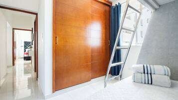 Quarto com guarda-roupa de madeira, escada e cama com almofadas.