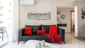 A modern living room with a black leather sofa, red cushions, a zebra-patterned vase, and a large abstract painting on the wall.