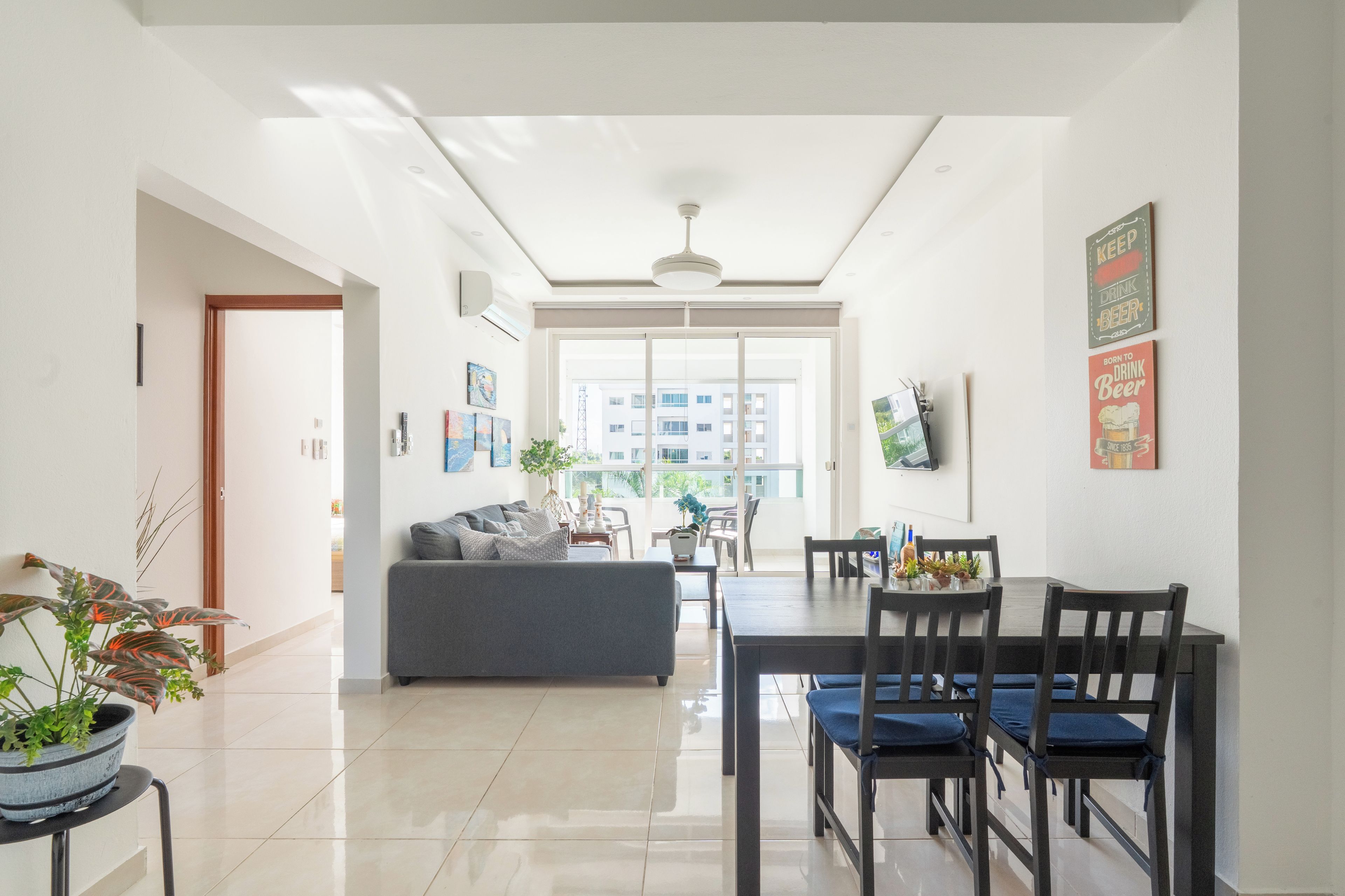Uma sala de estar moderna com sofá, mesa de jantar, cadeiras e vista através de uma grande janela.
