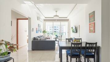 Uma sala de estar moderna com sofá, mesa de jantar, cadeiras e vista através de uma grande janela.