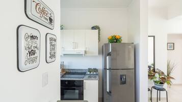 Cozinha moderna com eletrodomésticos de aço inoxidável, bancada de granito e arte decorativa na parede.