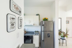 Cozinha moderna com eletrodomésticos de aço inoxidável, bancada de granito e arte decorativa na parede.
