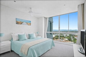 A bedroom with a bed, a nightstand, a TV, a window with a view, and a ceiling fan. - Coastal Heights | Broadwater Views (Southport)