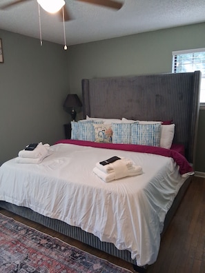 Una cama bien hecha con edredón blanco, almohadas y toallas dobladas.