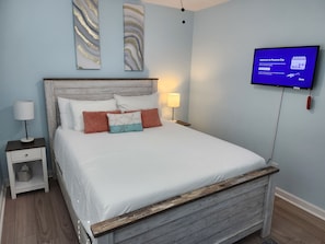 A bedroom with a bed, a nightstand, a TV, and wall art. - The Cozy Farmhouse Retreat (Chipley)