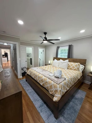 Une chambre à coucher avec un lit, des tables de chevet, un ventilateur de plafond et une fenêtre.