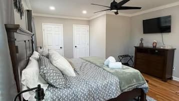 Une chambre à coucher comprenant un lit, un bureau, une chaise, une commode, un téléviseur et un ventilateur de plafond.