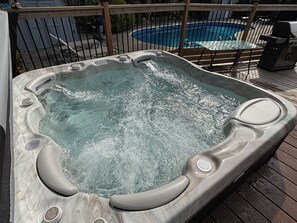 A hot tub on a wooden deck with a pool in the background. - Poolside Retreat | Private Pool, Hot Tub & Huge Deck in Niagara-on-the-Lake (Niagara-on-the-Lake)