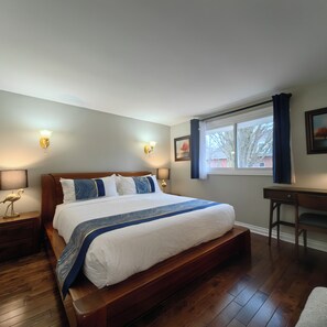 A bedroom with a large bed, bedside lamps, a desk, and a window with curtains. - Poolside Retreat | Private Pool, Hot Tub & Huge Deck in Niagara-on-the-Lake (Niagara-on-the-Lake)
