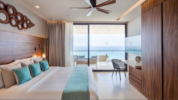 Habitación de hotel con una cama grande, un escritorio, una silla y vista al océano.