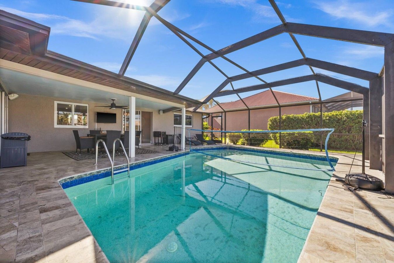 Ein überdachter Außenpool mit Terrassenbereich, inklusive Tisch und Stühlen.