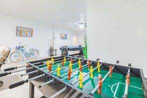 A room with a foosball table, a bicycle, and a ping pong table. - RGB Pool & Game Room | Steps to Beach | 3BR Oasis (Fort Myers Beach)