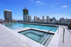 A rooftop pool with a city skyline in the background. - NEW | High-Rise 1BR Den, Rooftop Pool & Gym 402 (Miami)