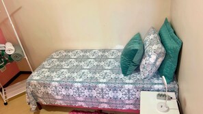A small bed with patterned bedding and two pillows, a power outlet, and a white charging station. - Pink Room near PUC Arena da Baixada, botanical garden and downtown Curitiba. (Curitiba)