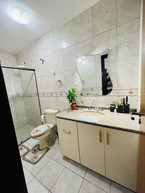A bathroom with a toilet, sink, mirror, shower, and a potted plant. - Pink Room near PUC Arena da Baixada, botanical garden and downtown Curitiba. (Curitiba)