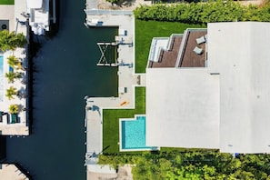 Vista aèria d'una propietat a primera línia de mar amb piscina, moll i vegetació adjacenta.