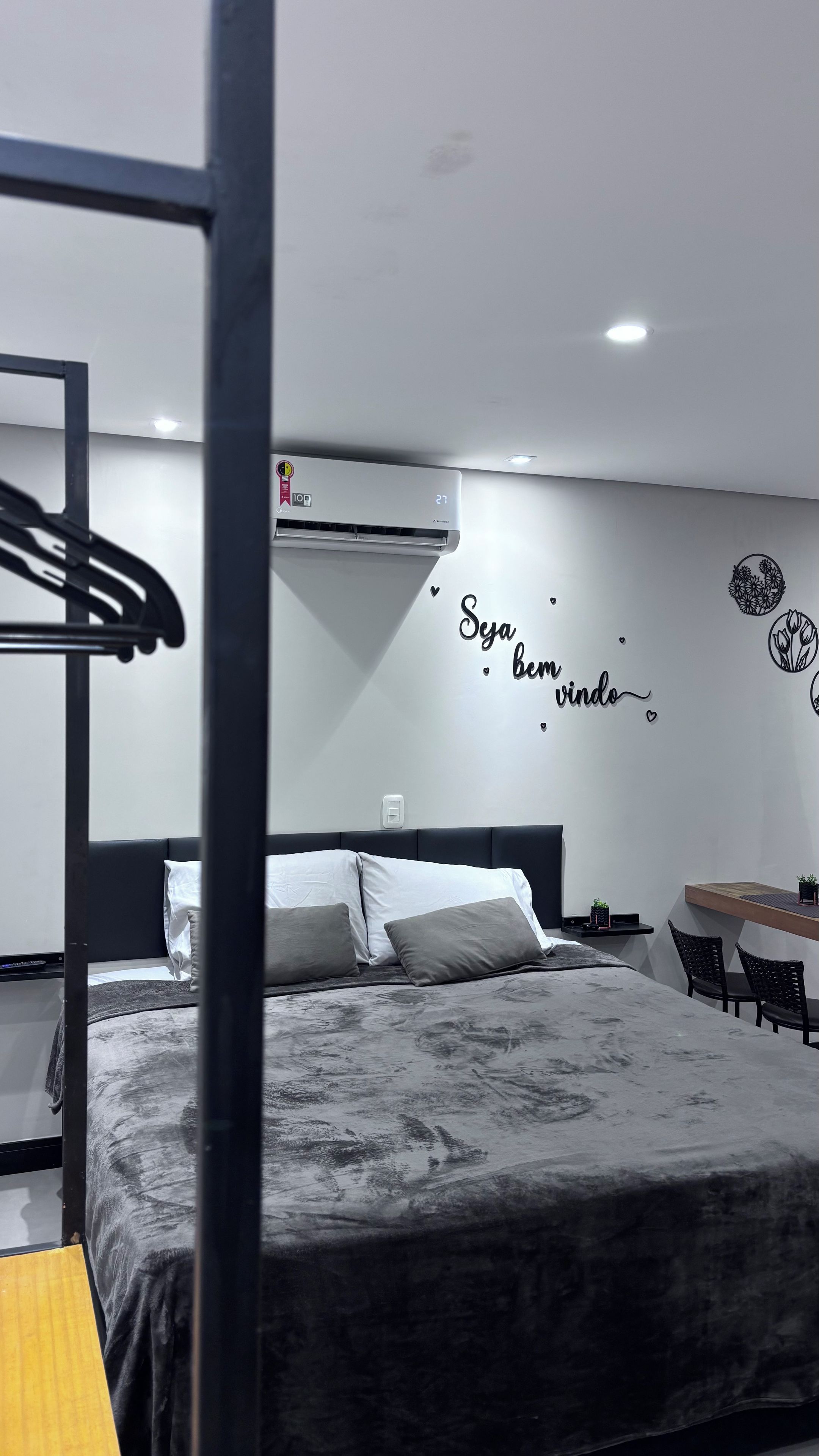 A modern hotel room with a bunk bed, a desk with chairs, and a wall with a motivational quote.