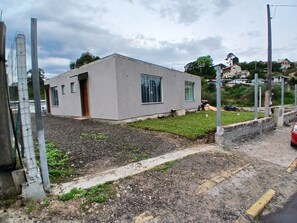 Un edificio moderno con tetto piatto, un piccolo giardino antistante e vialetto lastricato.
