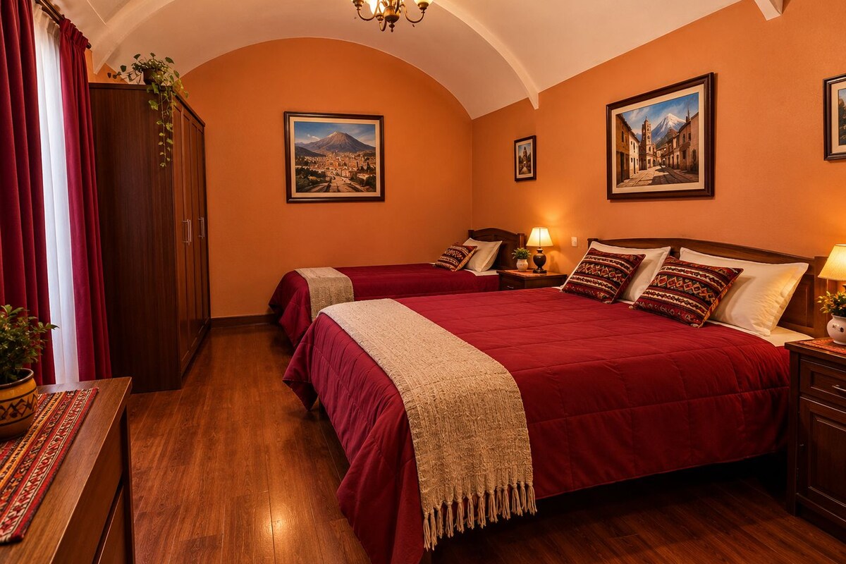 A hotel room with a large bed, two bedside tables, a wooden floor, and a chandelier.